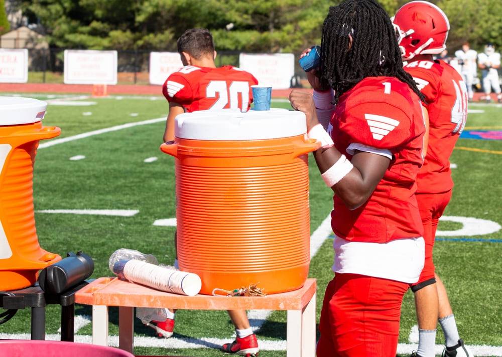 football player drinking water on sidelines